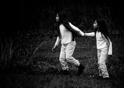 Full length of siblings holding hands on grassy field