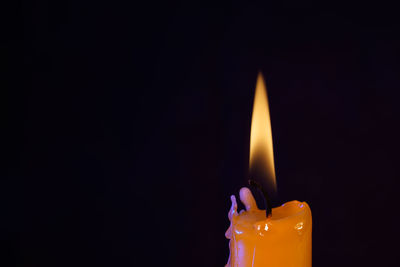 Close-up of lit candle against black background