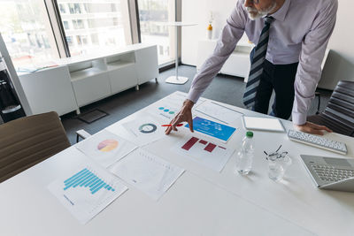 Businessman examining charts and graphs at desk in office