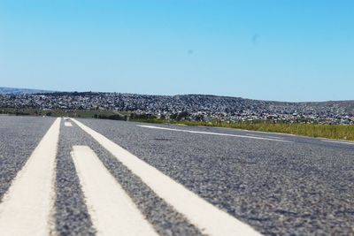 Road leading towards clear blue sky
