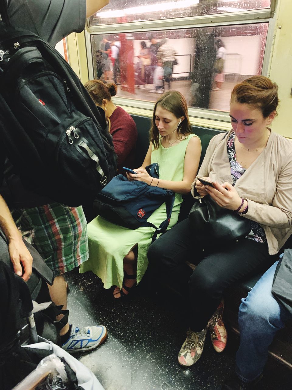 sitting, full length, casual clothing, mode of transportation, transportation, women, travel, public transportation, real people, people, group of people, adult, bag, lifestyles, technology, young adult, young women, mobile phone, vehicle interior, communication, subway train