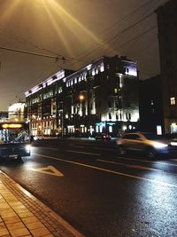 Illuminated railroad tracks by buildings in city at night