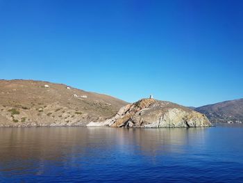 Scenic view of lake and mountains against clear blue sky