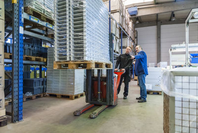 Worker in warehouse transporting goods on forklift