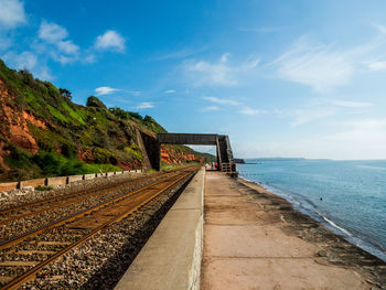 Railroad tracks by sea against sky