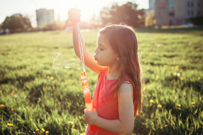 Girl holding bubbles while standing on field