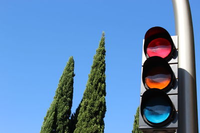 Low angle view of road sign against clear blue sky