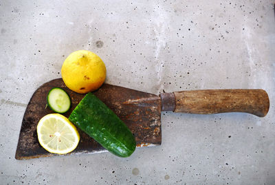 Directly above shot of lemons and cucumber on rusty axe
