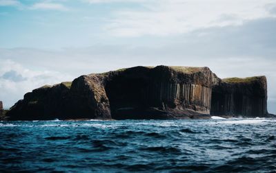 Rock formation in sea against sky