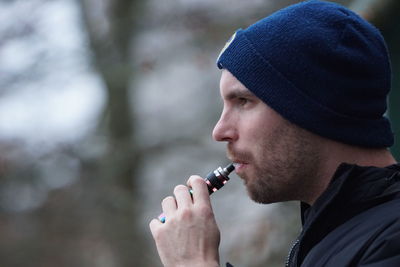 Side view of man smoking with electronic cigarette