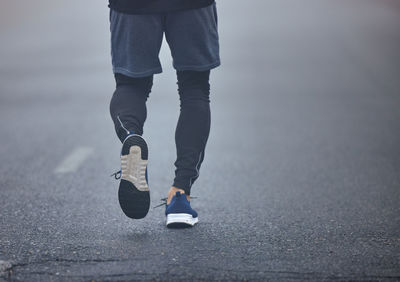 Low section of man walking on road