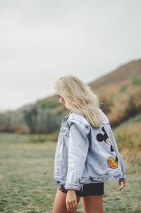 Woman walking on field against sky