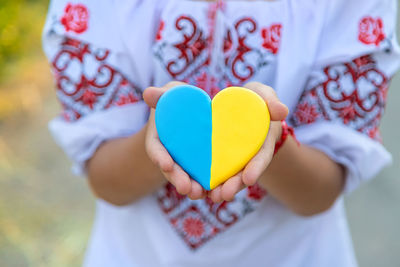 Midsection of woman holding heart shape