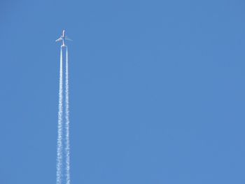 Low angle view of airplane flying against clear blue sky