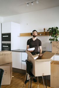 Portrait of man unpacking kitchen utensils from box at new home