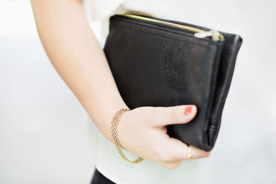 Midsection of woman holding clutch bag outdoors