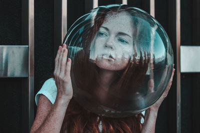 Close-up of thoughtful young woman wearing glass helmet in head against metallic railing