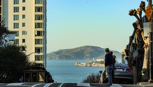 Man standing by cars on mountain against clear sky