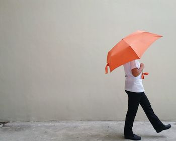 Full length of young woman standing against red umbrella