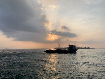 Ship sailing on sea against sky during sunset