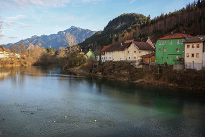 Houses by lake and buildings against sky