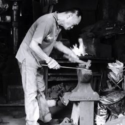 Full length of blacksmith working in old workshop