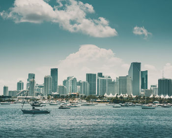 Sea by modern buildings in city against sky