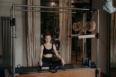 Full length portrait of woman sitting at gym