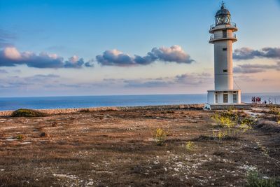 Lighthouse by sea against sky