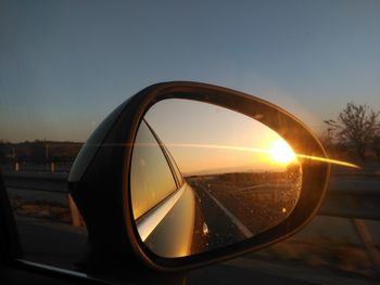 Reflection of sunset in side-view mirror