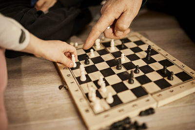 Grandfather pointing at girl holding chess piece