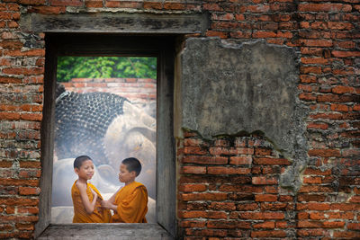 Portrait of friends standing against brick wall