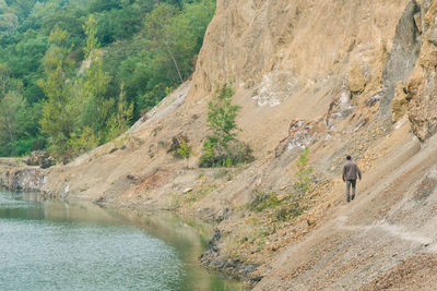 Rear view of man walking on steep at lakeshore