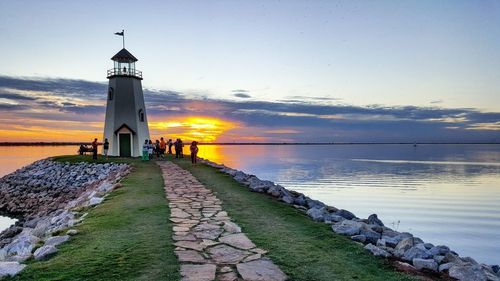 View of lighthouse against calm sea at sunset