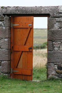 Close-up of wooden door on field against sky