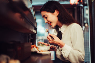 Side view of young woman using mobile phone in restaurant