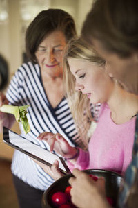 Three generation females checking out recipe on digital tablet in kitchen