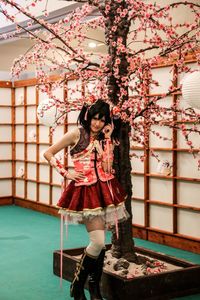 Full length of young woman looking away while standing against wall