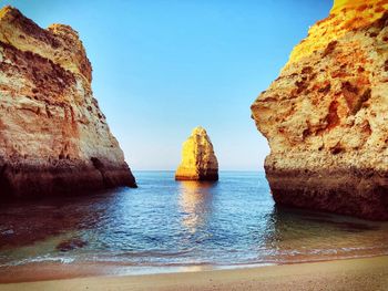 Rock formations in sea against blue sky