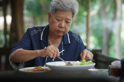 Portrait of senior man preparing food on table