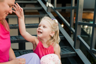 Portrait of smiling young woman sitting on railing