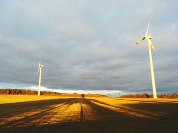 Wind turbines on field against sky