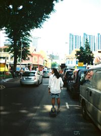 Rear view of woman walking on road in city