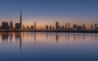 Reflection of burj khalifa and modern building in sea at sunset