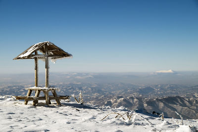 Lifeguard hut on snow covered land against sky