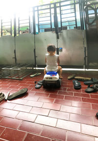 Rear view of boy sitting on tiled floor