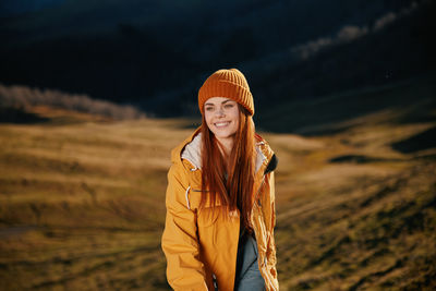 Portrait of young woman standing against mountain