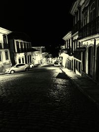 Empty alley amidst buildings at night