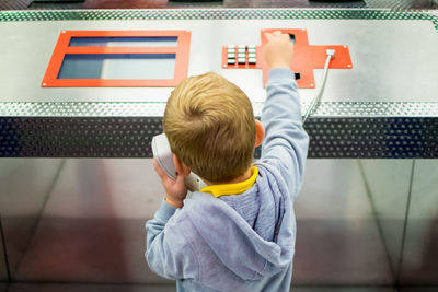 High angle view of boy using pay phone