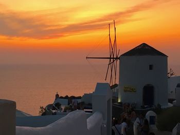 Buildings by sea against sky during sunset